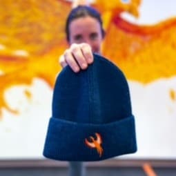 Juliana in a yoga pose holding up our RI Hot Yoga beanie